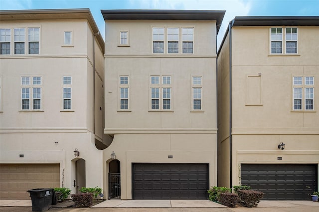 view of property featuring concrete driveway, an attached garage, and stucco siding
