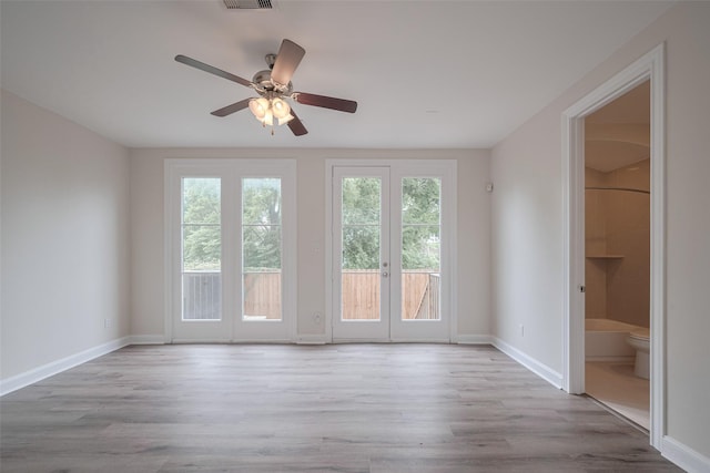 empty room with baseboards, a ceiling fan, wood finished floors, and visible vents