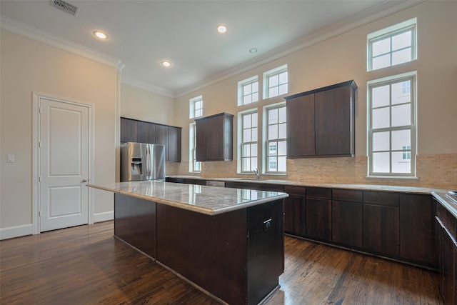 kitchen with decorative backsplash, visible vents, a center island, dark brown cabinets, and stainless steel fridge with ice dispenser
