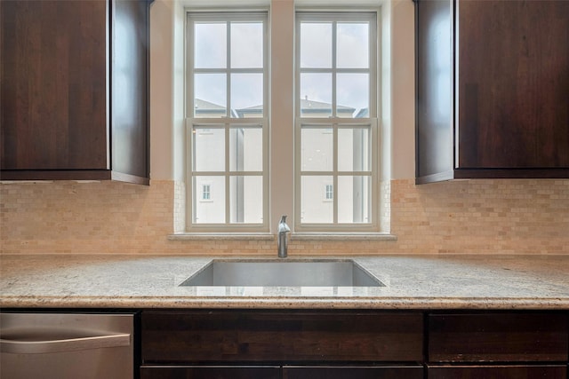 kitchen featuring a sink, dishwasher, dark brown cabinets, and tasteful backsplash