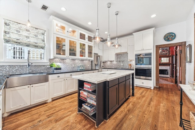 1101 Heights Blvd, Houston, TX 77008 - kitchen featuring stainless steel appliances, white cabinetry, a sink, decorative backsplash, and glass insert cabinets
