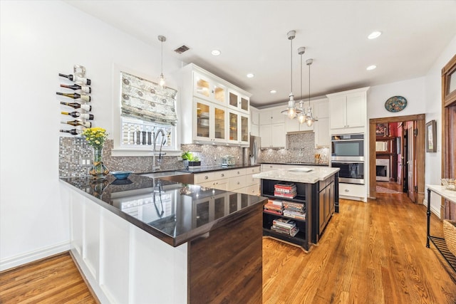 1101 Heights Blvd, Houston, TX 77008 - kitchen featuring appliances with stainless steel finishes, a sink, decorative backsplash, white cabinets, and glass insert cabinets