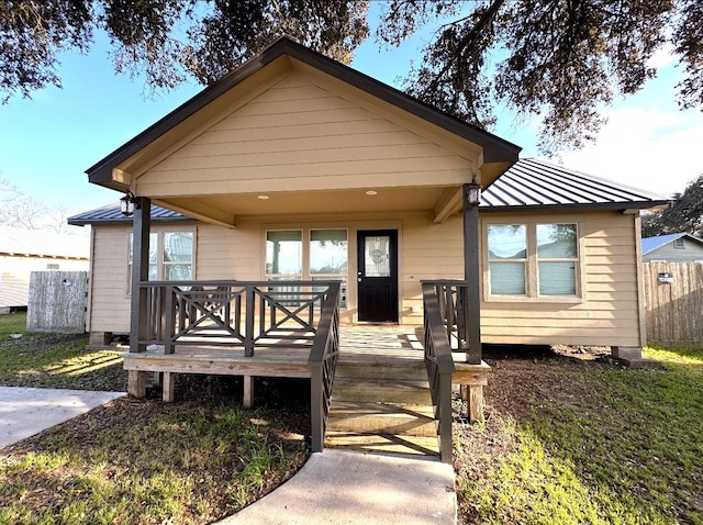 bungalow-style home featuring metal roof, fence, and a standing seam roof