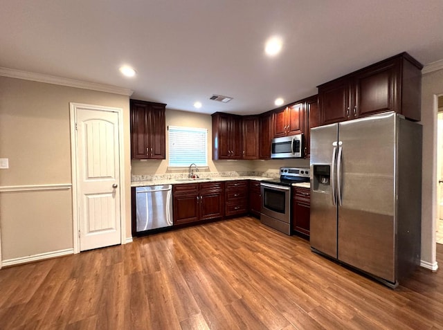 kitchen featuring light countertops, stainless steel appliances, a sink, visible vents, and wood finished floors