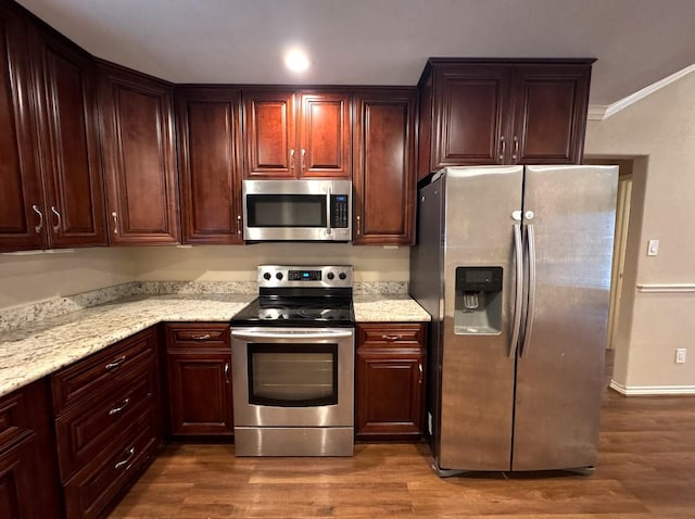 kitchen featuring dark wood finished floors, light stone counters, ornamental molding, and appliances with stainless steel finishes