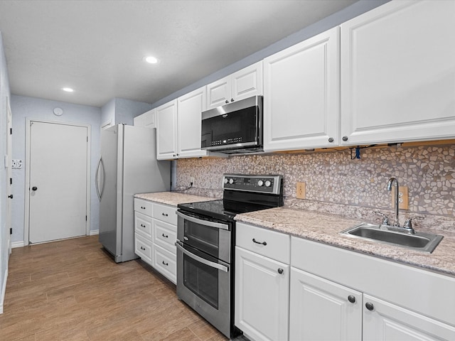 314 Lantana Dr, Texas City, TX 77591 - kitchen featuring white cabinetry, decorative backsplash, a sink, light wood finished floors, and appliances with stainless steel finishes