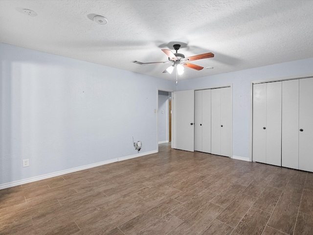 314 Lantana Dr, Texas City, TX 77591 - unfurnished bedroom with baseboards, multiple closets, a textured ceiling, ceiling fan, and wood finished floors