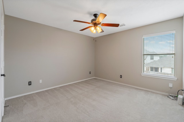 empty room with ceiling fan, light colored carpet, baseboards, and visible vents