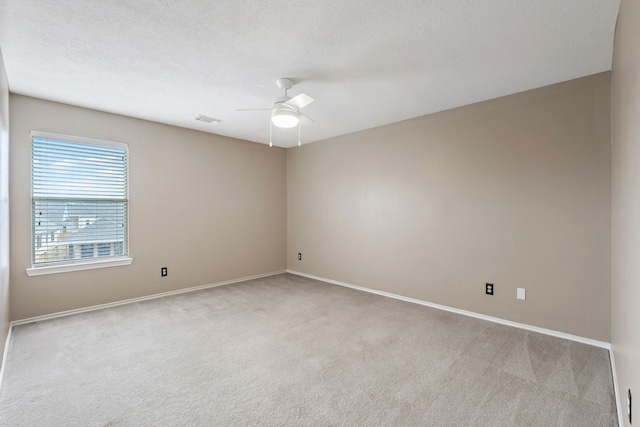 carpeted spare room with a ceiling fan, baseboards, and visible vents