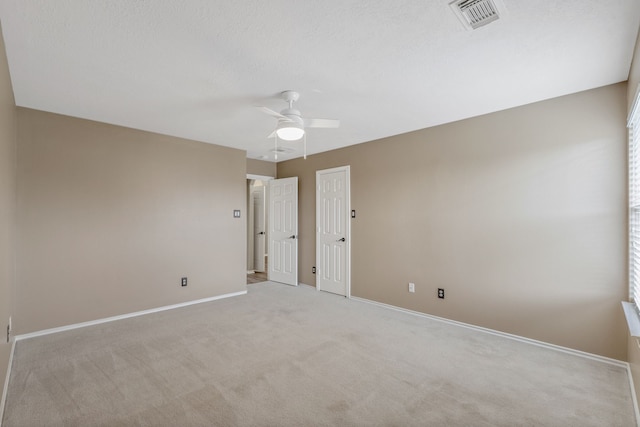 spare room with visible vents, carpet flooring, baseboards, and ceiling fan