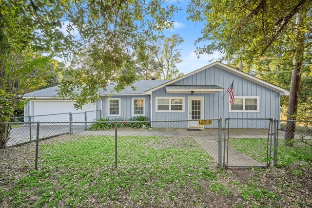 view of front of house with an attached garage, board and batten siding, driveway, a fenced front yard, and a gate