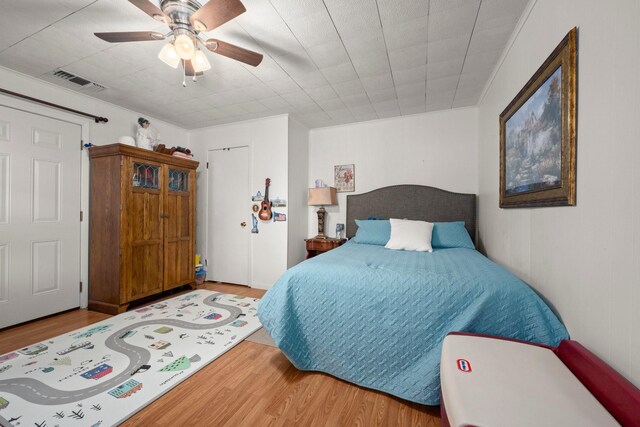 bedroom with visible vents, wood finished floors, ceiling fan, and ornamental molding
