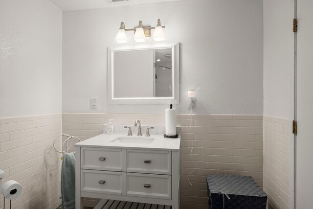 bathroom featuring wainscoting, visible vents, vanity, and tile walls