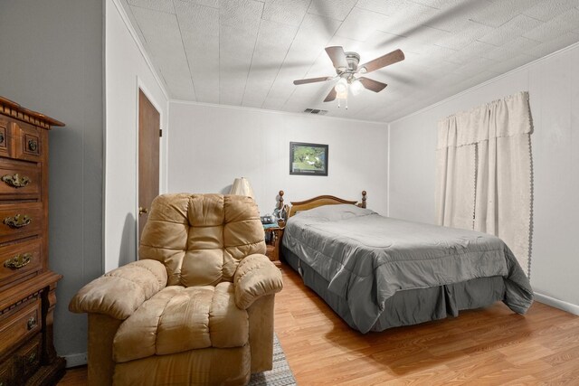 bedroom with a ceiling fan, light wood-style flooring, ornamental molding, and visible vents