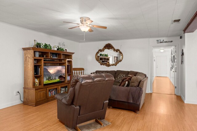 living room featuring baseboards, light wood-type flooring, visible vents, and ceiling fan