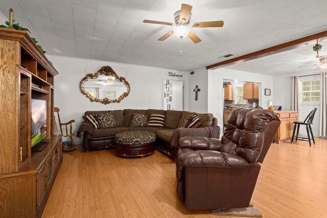 living room with light wood-style flooring, visible vents, and ceiling fan