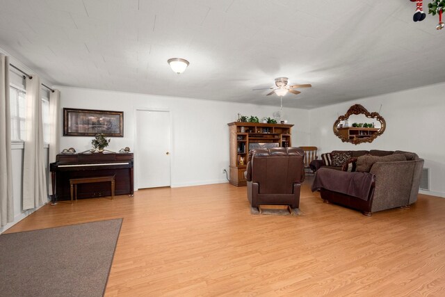living room with light wood finished floors, baseboards, visible vents, and ceiling fan