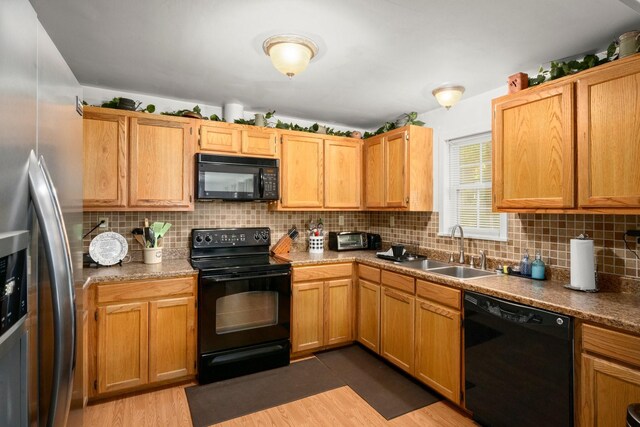 kitchen featuring backsplash, a sink, black appliances, and wood finished floors