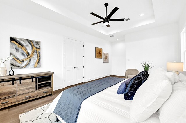 bedroom with baseboards, a tray ceiling, wood finished floors, and recessed lighting