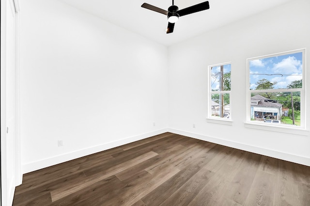 unfurnished room with baseboards, ceiling fan, and dark wood finished floors