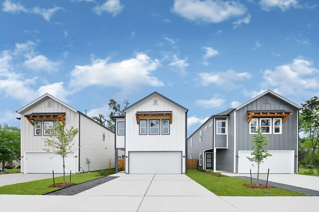 view of front of home with an attached garage, a front lawn, board and batten siding, and concrete driveway