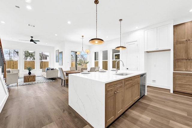kitchen featuring visible vents, a sink, wood finished floors, and dishwasher