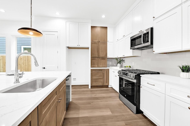 kitchen featuring light wood finished floors, white cabinets, a sink, and stainless steel appliances