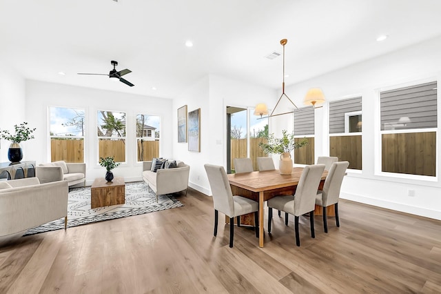 dining room with wood finished floors, ceiling fan with notable chandelier, baseboards, visible vents, and recessed lighting