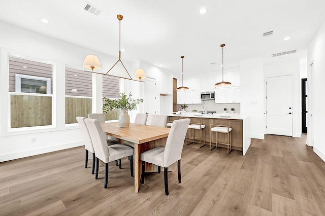 dining space featuring light wood finished floors, visible vents, and recessed lighting