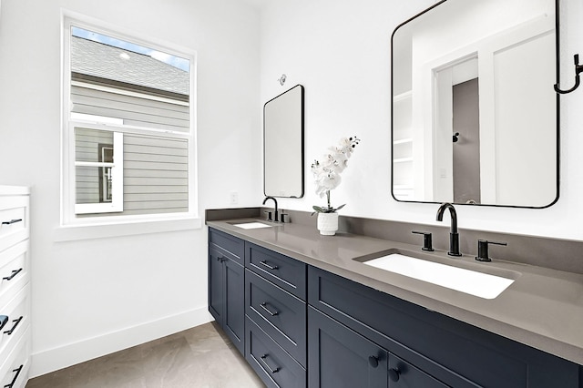 bathroom featuring baseboards, double vanity, and a sink