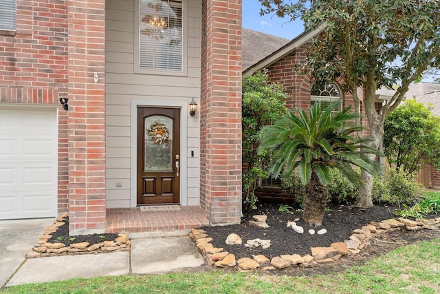 entrance to property featuring brick siding, a shingled roof, and a garage