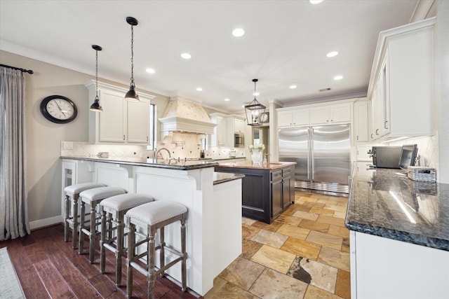 271 W Pines Dr, Montgomery, TX 77356 - kitchen with built in appliances, custom range hood, backsplash, a kitchen bar, and ornamental molding