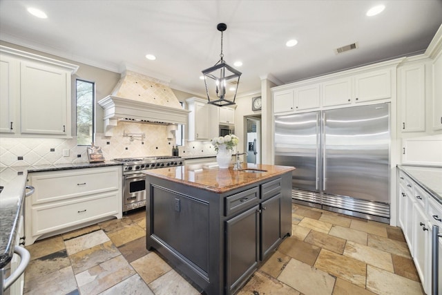 271 W Pines Dr, Montgomery, TX 77356 - kitchen featuring high end appliances, custom range hood, crown molding, stone tile flooring, and a sink