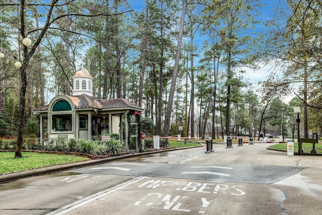 271 W Pines Dr, Montgomery, TX 77356 - view of asphalt road with a gated entry, traffic signs, curbs, and street lights