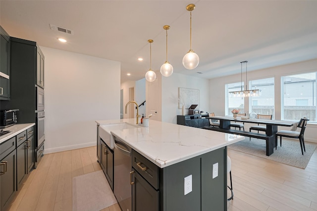 9603 Crescent Mill Dr, Missouri City, TX 77459 - kitchen with visible vents, a sink, a kitchen island with sink, light wood finished floors, and stainless steel appliances