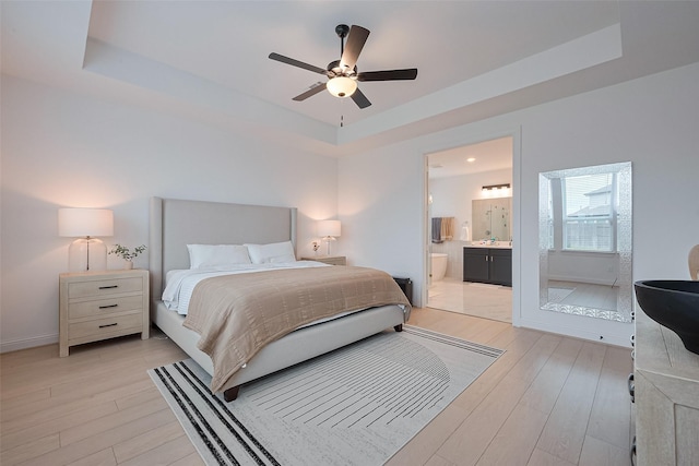 9603 Crescent Mill Dr, Missouri City, TX 77459 - bedroom featuring a tray ceiling, light wood-type flooring, ensuite bath, a ceiling fan, and baseboards