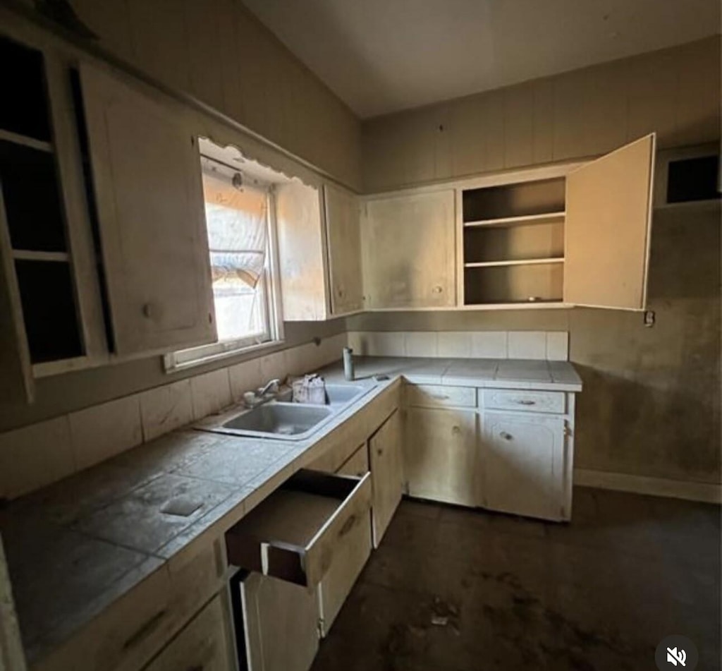 kitchen with open shelves, tile counters, and a sink