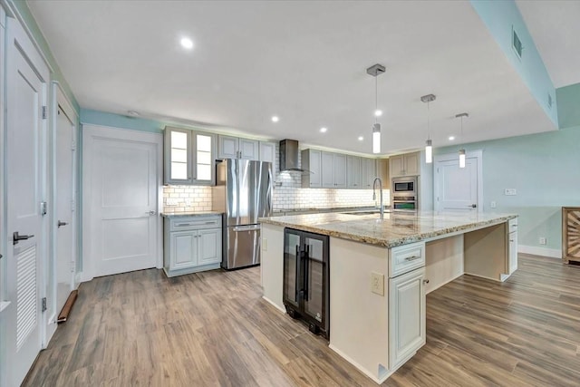 126 Tamana Dr, Tiki Island, TX 77554 - kitchen featuring wood finished floors, stainless steel appliances, a sink, beverage cooler, and wall chimney range hood
