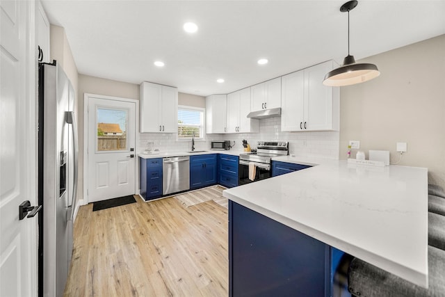 2008 71st St, Galveston, TX 77551 - kitchen featuring stainless steel appliances, blue cabinetry, under cabinet range hood, a peninsula, and a sink