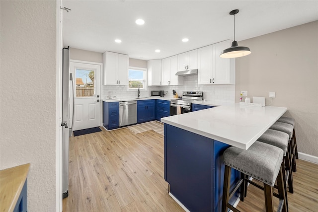 2008 71st St, Galveston, TX 77551 - kitchen with stainless steel appliances, blue cabinets, a kitchen bar, a peninsula, and a sink