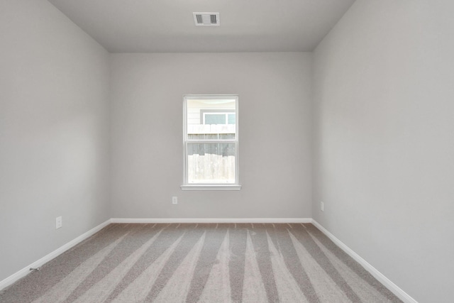 unfurnished room with baseboards, visible vents, and carpet