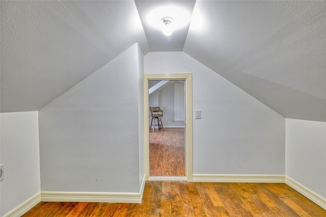 49 Regency Pt, Conroe, TX 77356 - additional living space featuring baseboards, lofted ceiling, wood finished floors, and a textured ceiling