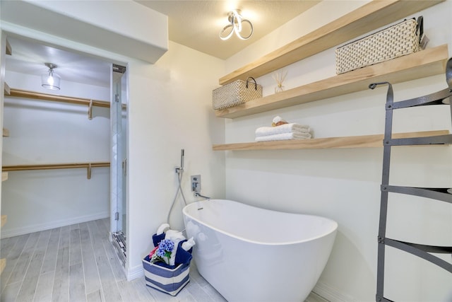 49 Regency Pt, Conroe, TX 77356 - bathroom featuring a spacious closet, a freestanding tub, baseboards, and wood finished floors