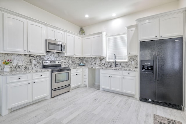 49 Regency Pt, Conroe, TX 77356 - kitchen featuring white cabinetry, tasteful backsplash, a sink, light stone counters, and appliances with stainless steel finishes