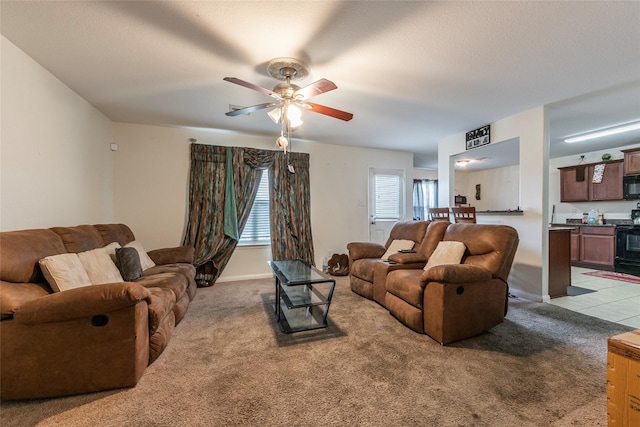 carpeted living room featuring baseboards and ceiling fan