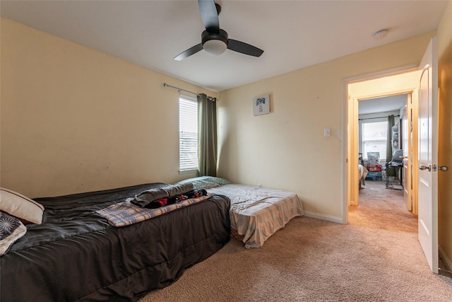 bedroom with baseboards, multiple windows, light colored carpet, and ceiling fan