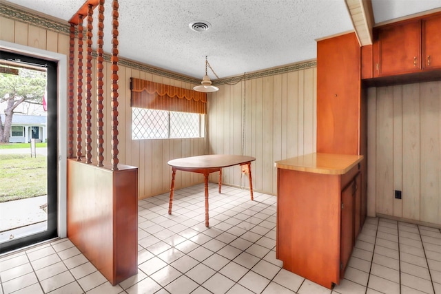 2509 Bayou Ave, Baytown, TX 77520 - kitchen featuring a textured ceiling, wooden walls, light countertops, light tile patterned floors, and decorative light fixtures