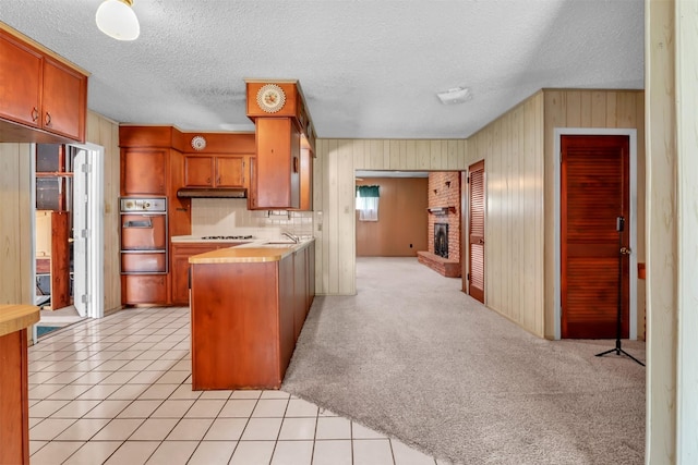 2509 Bayou Ave, Baytown, TX 77520 - kitchen with oven, a warming drawer, under cabinet range hood, light countertops, and wooden walls