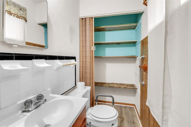 2509 Bayou Ave, Baytown, TX 77520 - bathroom featuring a sink, wood finished floors, toilet, and tile walls