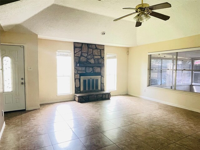 2503 Radcliffe Dr, Sugar Land, TX 77498 - unfurnished living room featuring ceiling fan, a textured ceiling, lofted ceiling, tile patterned floors, and a stone fireplace